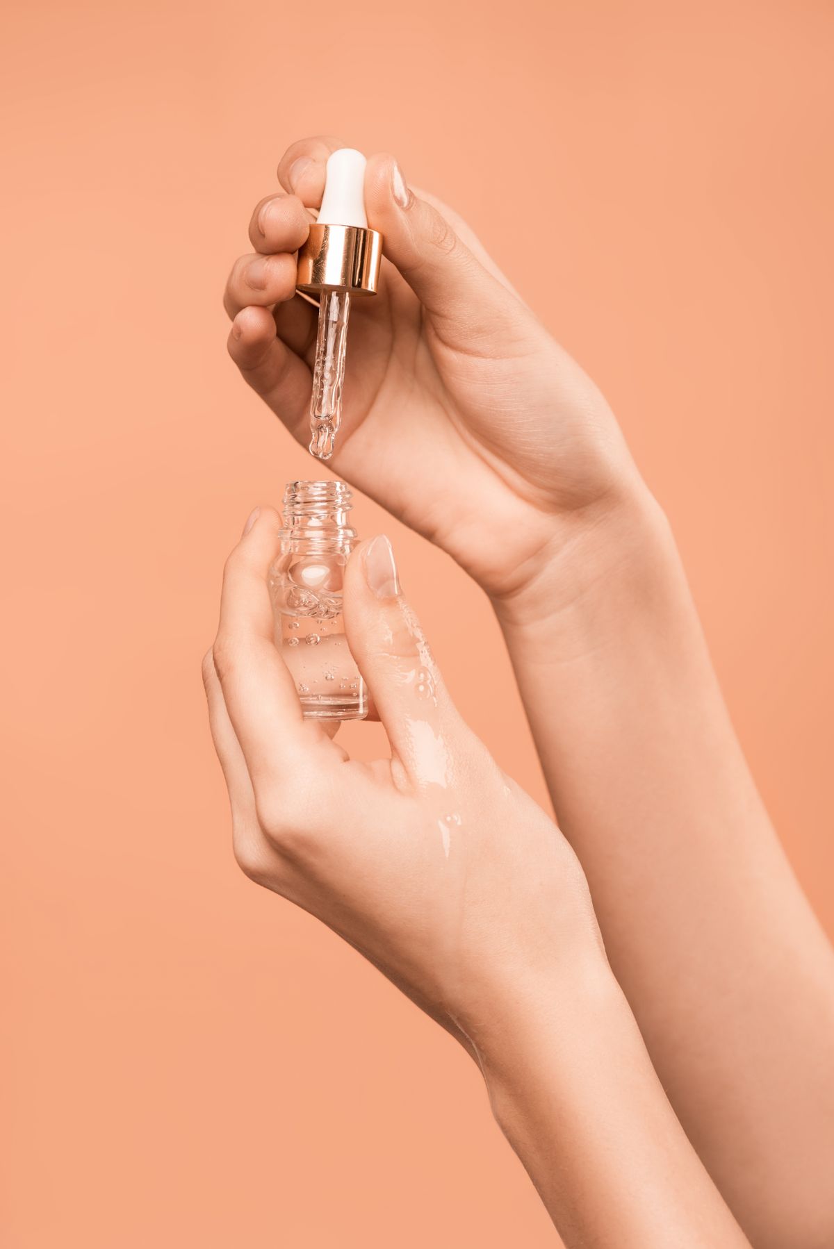 mãos segurando conta-gotas com sérum de peptídeos