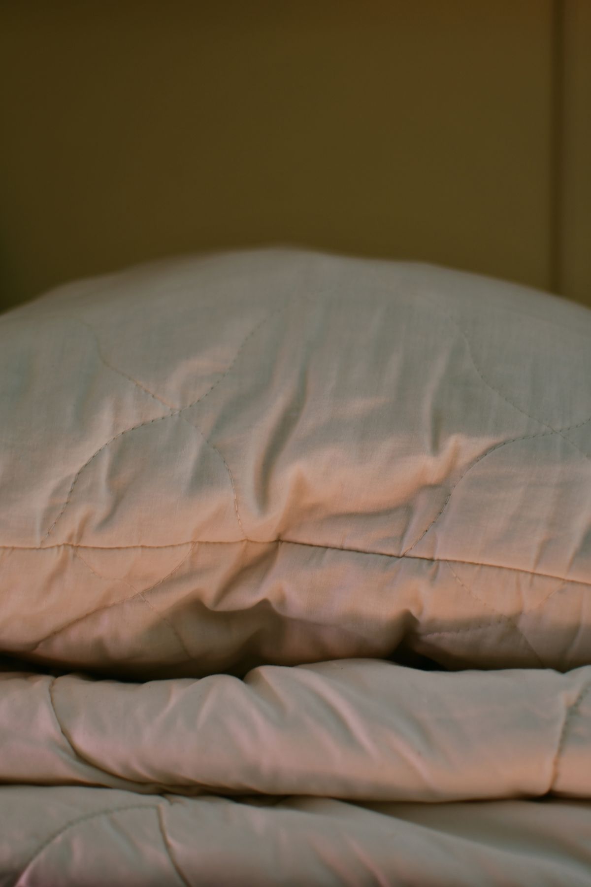 Travesseiro amassado na cama, ilustrando o efeito da posição para dormir na pele do rosto