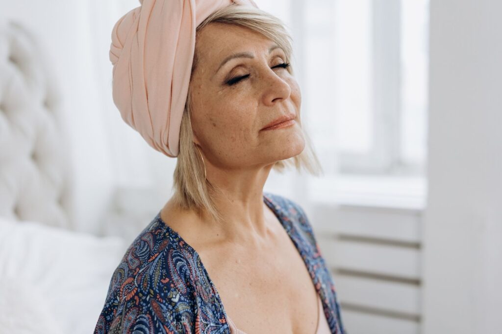 Mulher madura de olhos fechados cuidando da pele do rosto