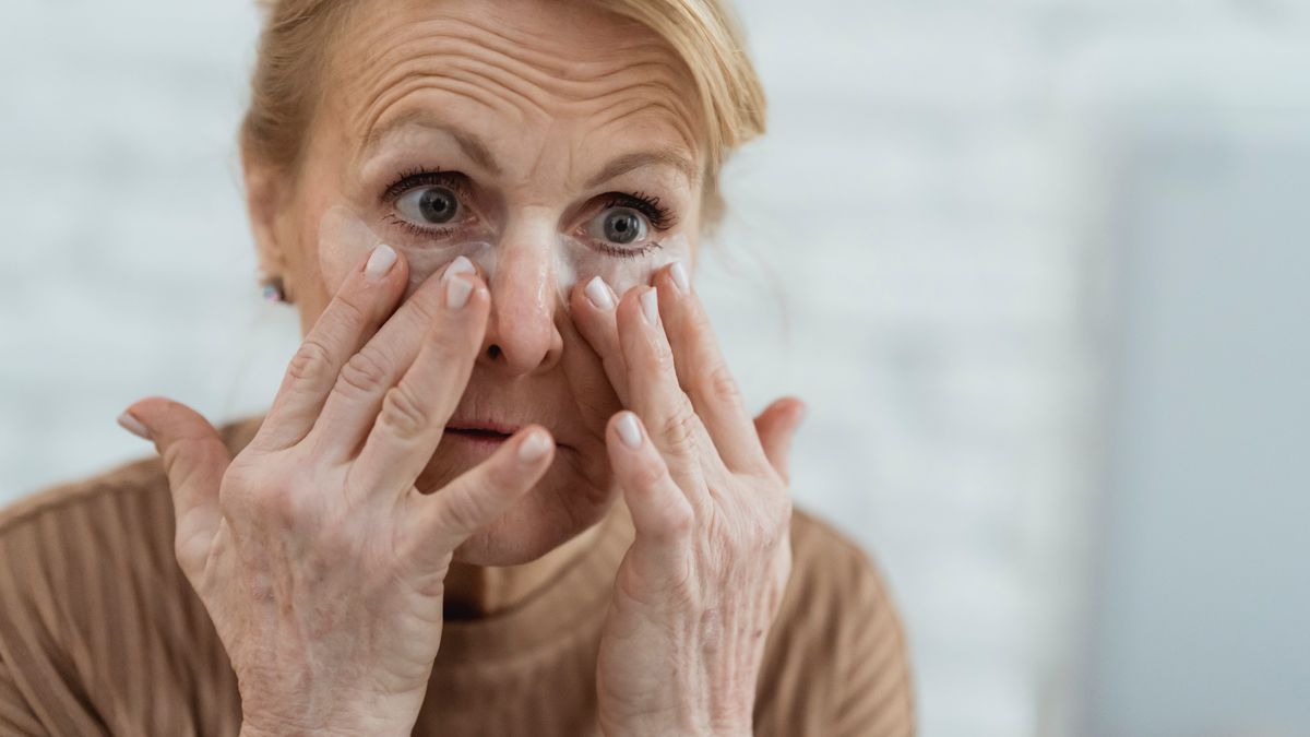 mulher madura aplicando creme para os olhos