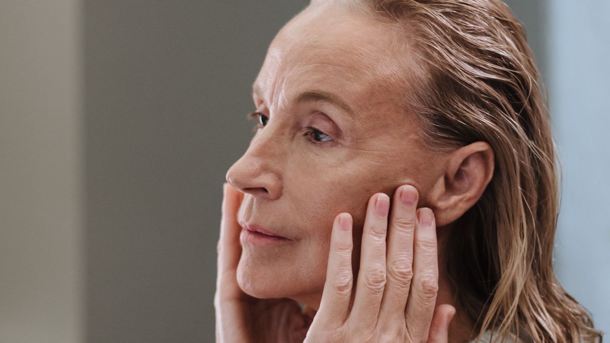 mulher tocando o rosto avaliando textura da pele antes do dermaplaning