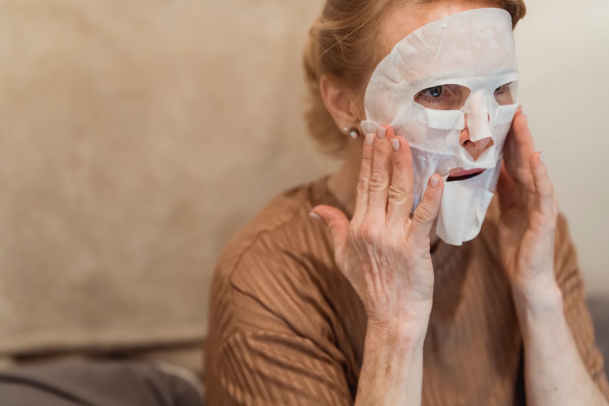 mulher madura usando máscara facial suave como parte da rotina de esfoliação enzimática