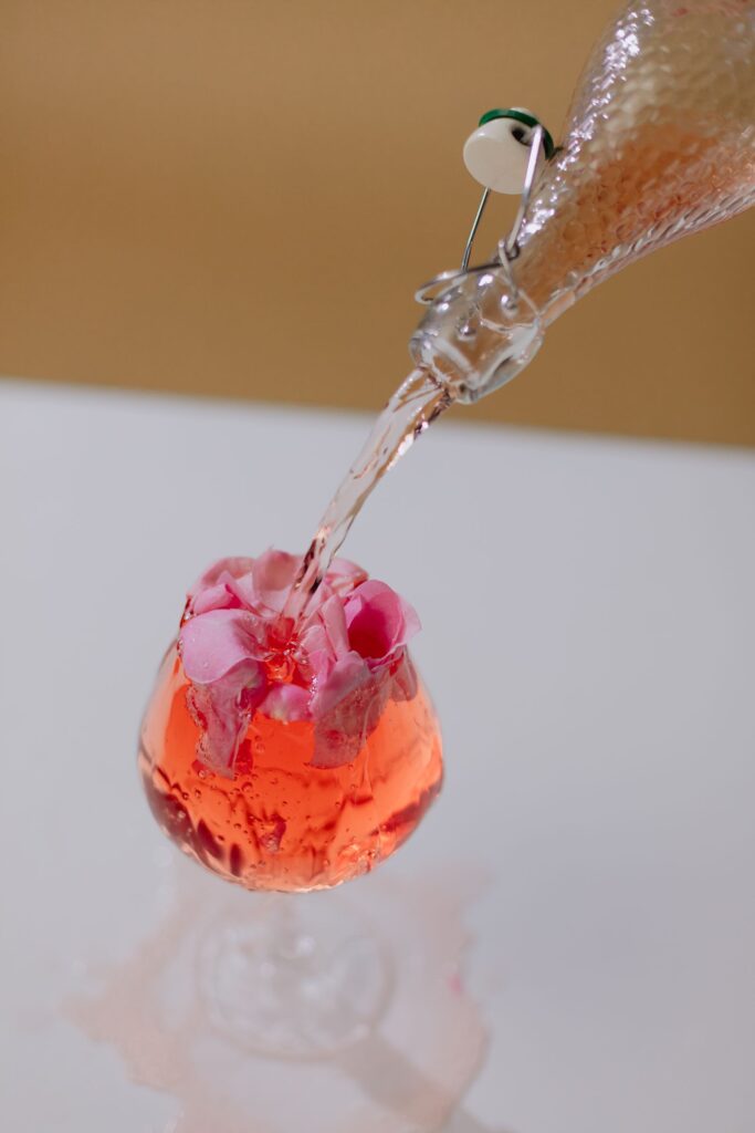 Líquido rosado sendo servido sobre pétalas de rosa