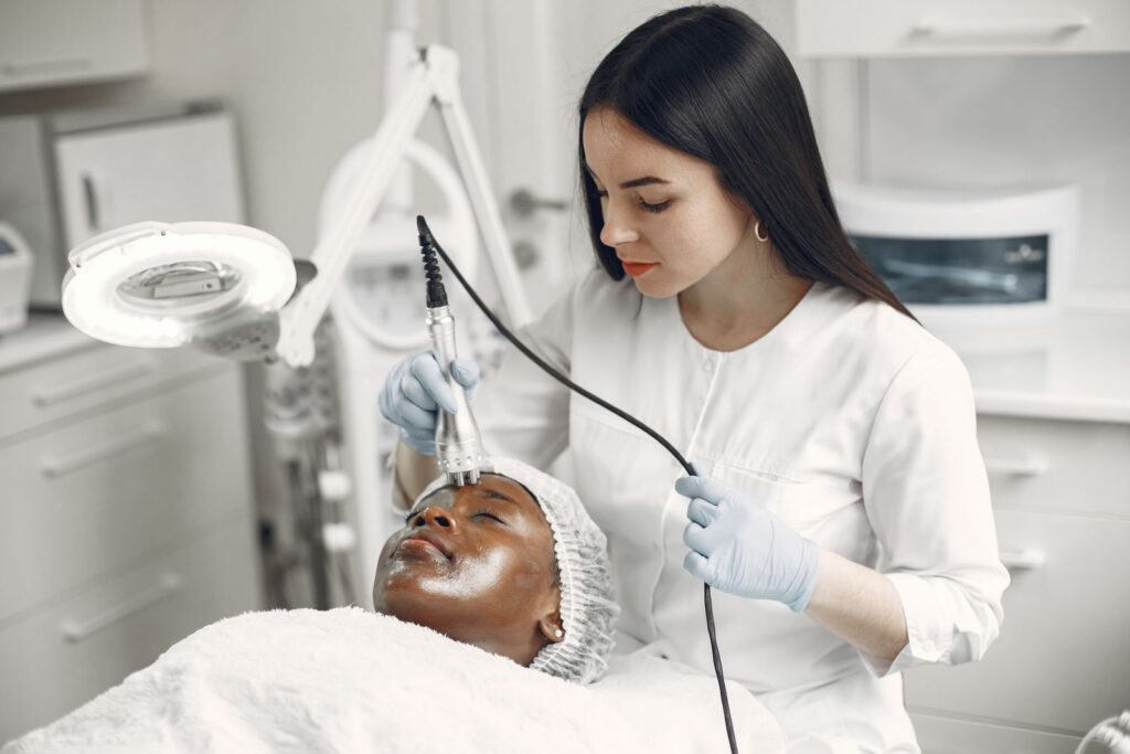 Dermatologista realizando procedimento na pele do rosto em consultório