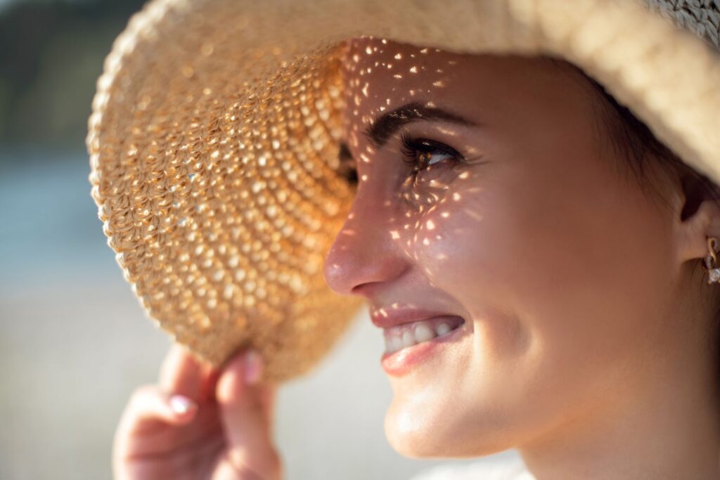 Mulher de chapéu com o rosto exposto ao sol
