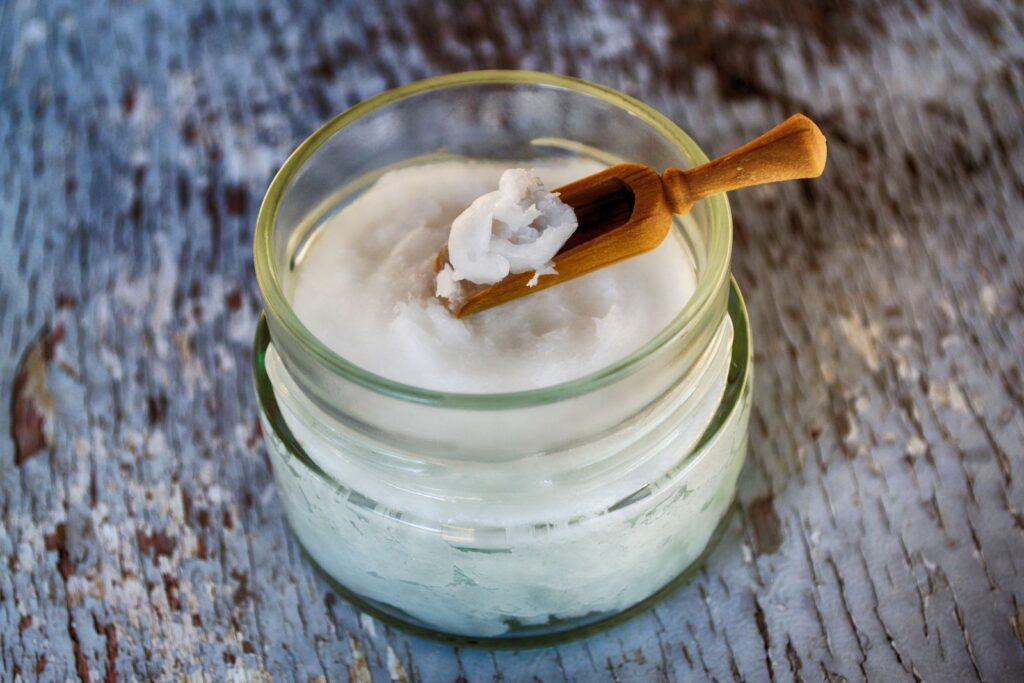 Pote de vidro com óleo de coco sólido e colher de madeira