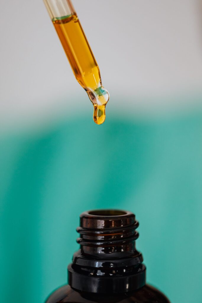Conta-gotas com óleo facial dourado sobre frasco