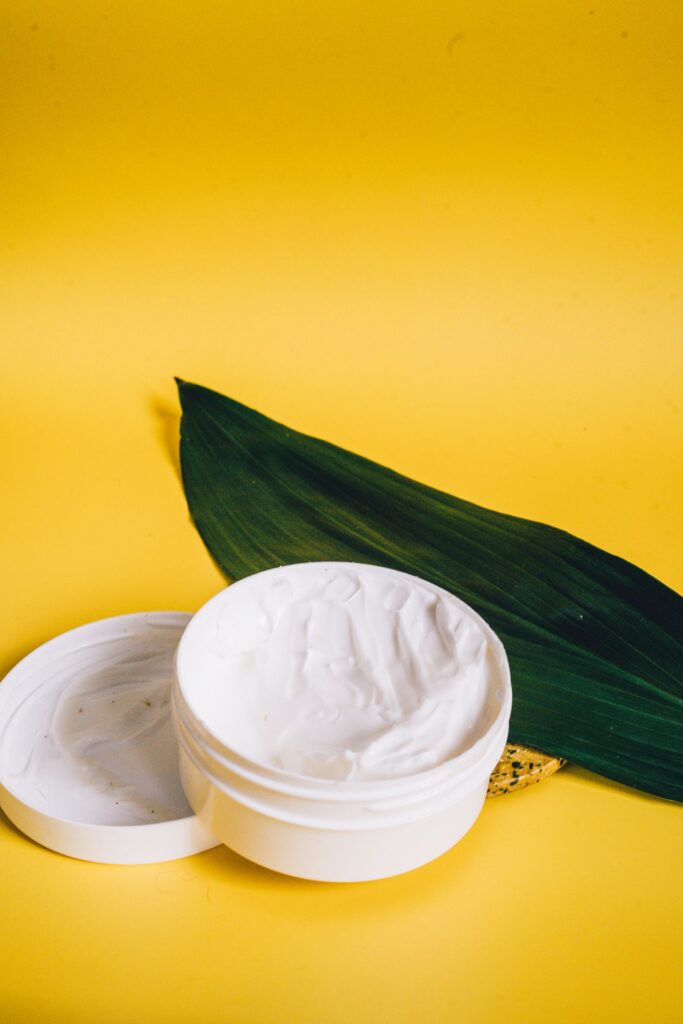 Pote aberto de creme com folha verde