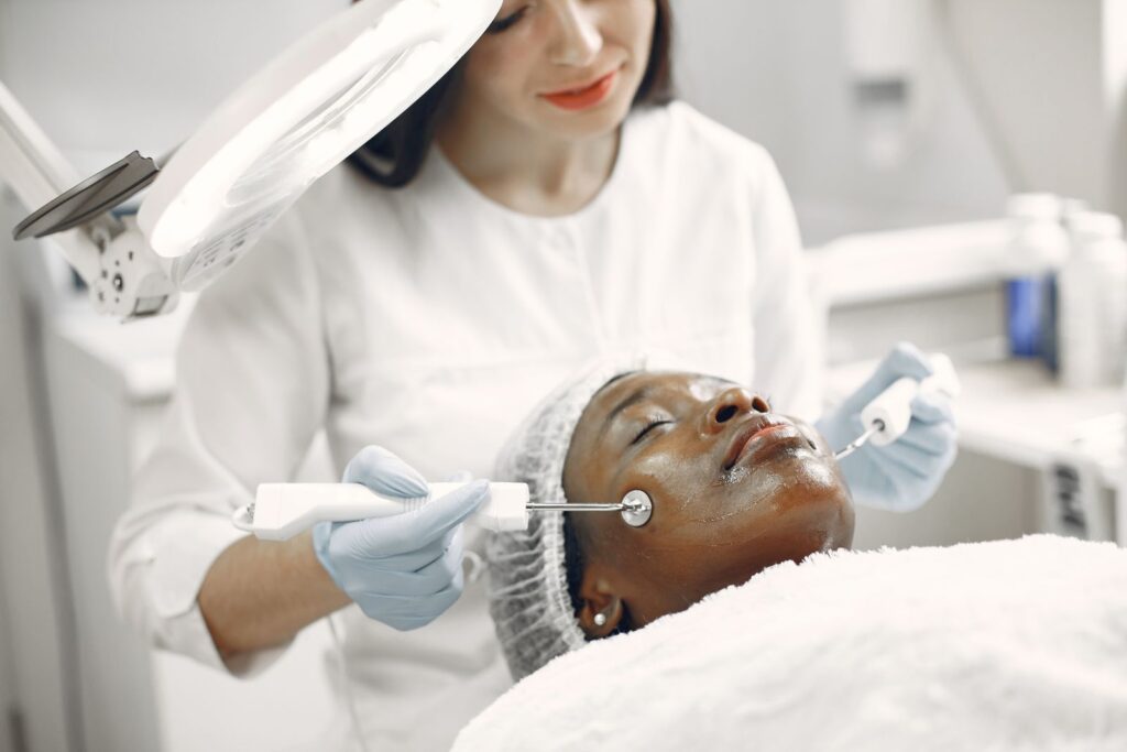 Profissional examinando e tratando a pele do rosto de uma paciente