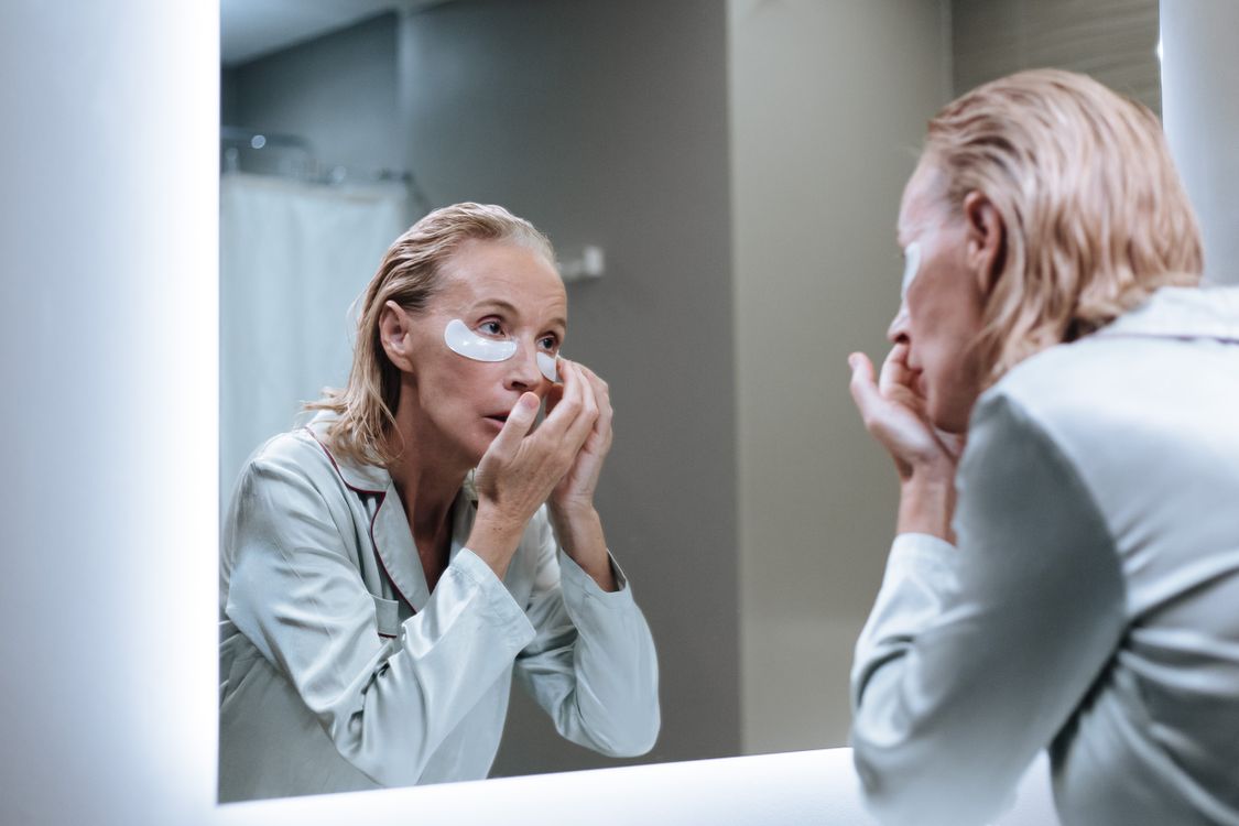 Mulher de pele madura aplicando produto de skincare pela manhã