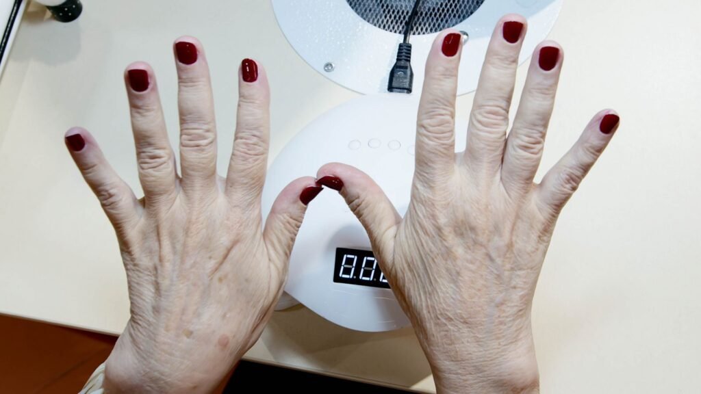 Mãos de mulher madura com esmalte em cabine de secagem