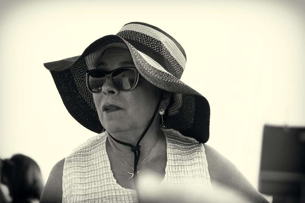 Mulher madura de chapéu e óculos se protegendo do sol